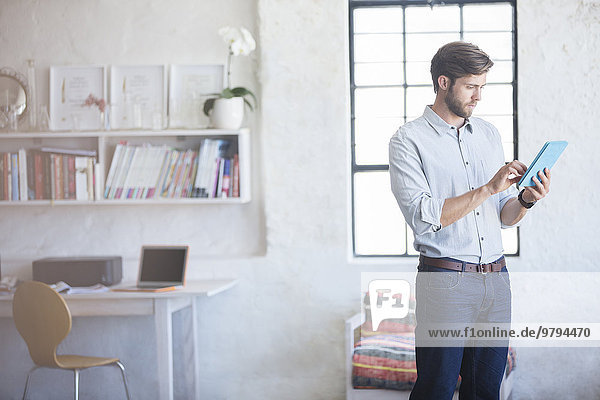Mann mit digitalem Tablett stehend im Home-Office