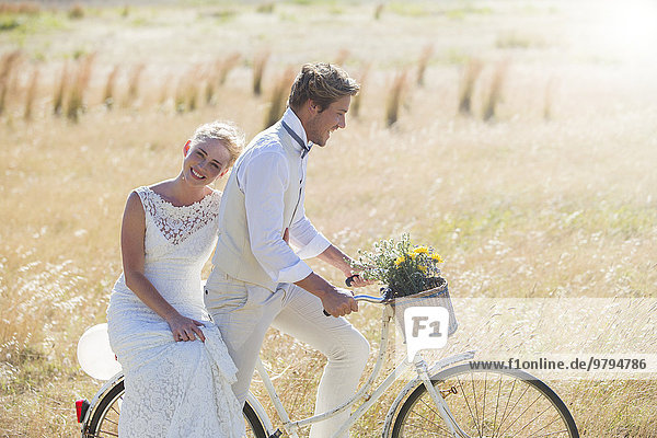 Young couple riding bike in meadow
