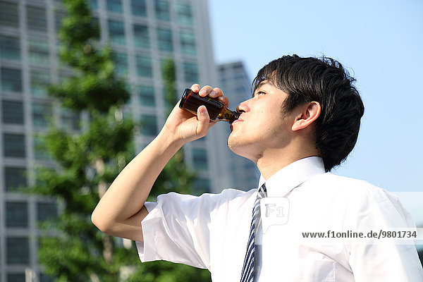 Japanese businessman drinking energy drink in the hot Japanese Summer