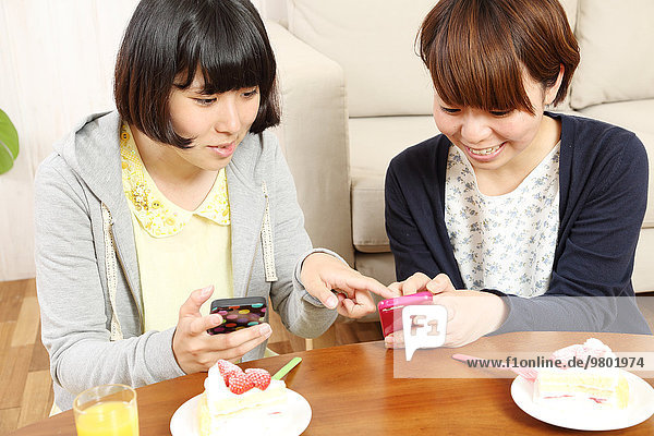Young Japanese girls having a piece of cake together in the living room