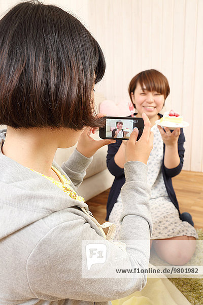Young Japanese girls having a piece of cake together in the living room
