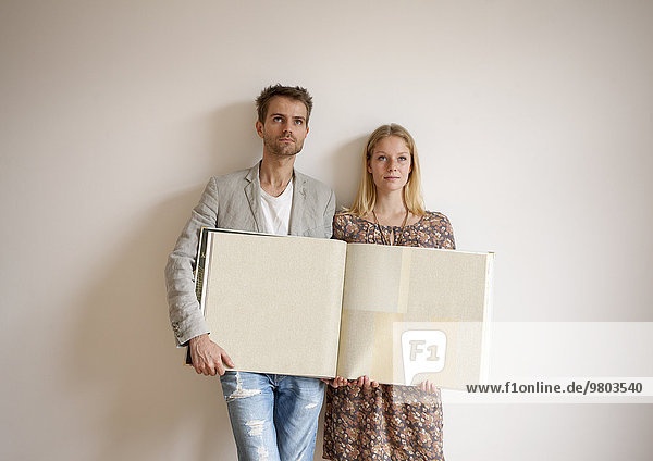 Junges Paar mit Tapetenbuch in neuer Wohnung
