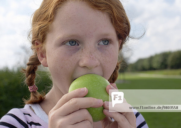 Rothaarige Mädchen isst einen Apfel