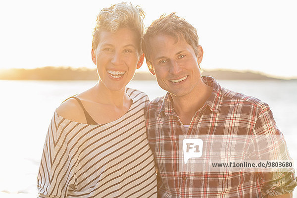 Porträt eines glücklichen Paares am Strand bei Sonnenuntergang