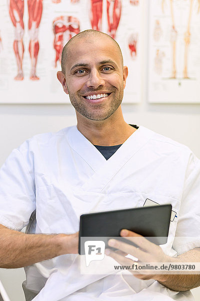 Porträt eines glücklichen Arztes mit digitaler Tablette in der orthopädischen Klinik