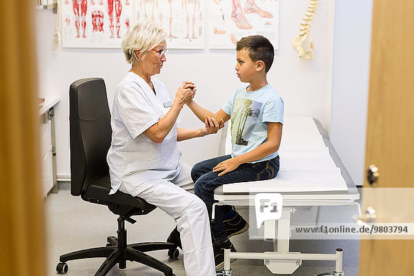 Senior-Orthopädin untersucht die Hand des Jungen in der Klinik