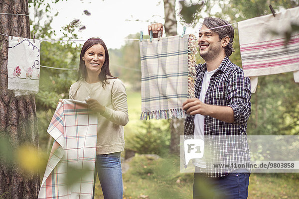Happy couple drying laundry in yard