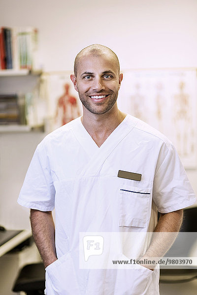 Portrait eines lächelnden orthopädischen Chirurgen mit Händen in den Taschen in der Klinik