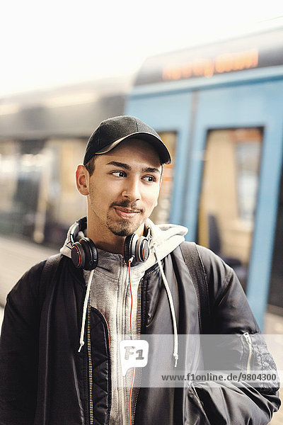 Thoughtful male university student standing at subway station
