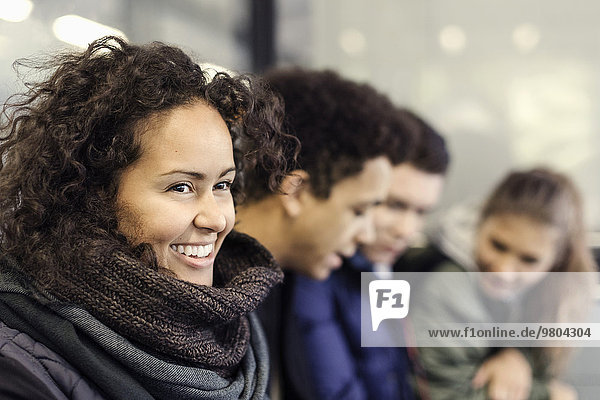 Happy university student sitting with friends at subway station