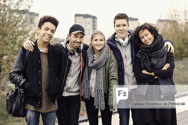 Portrait of smiling university students standing together on subway platform