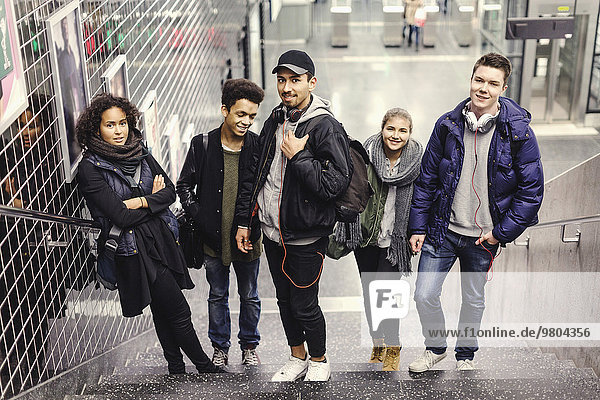 Ganzflächiges Porträt von Universitätsstudenten  die auf Stufen an der U-Bahn-Station stehen.