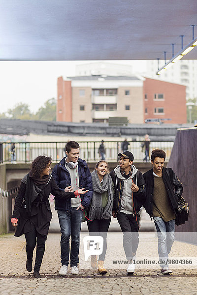 Full length of university students walking on footpath