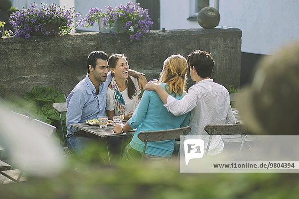 Lächelnde Paare beim Mittagessen im Outdoor-Café