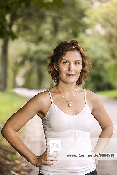 Portrait of fit woman standing with hands on hips at park