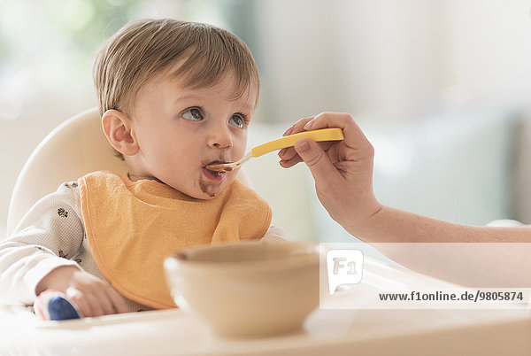 Mother feeding small boy (2-3) with spoon