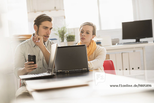 Young man and woman working together with laptop in office