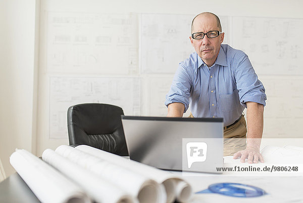 Portrait of mature architect using laptop in office