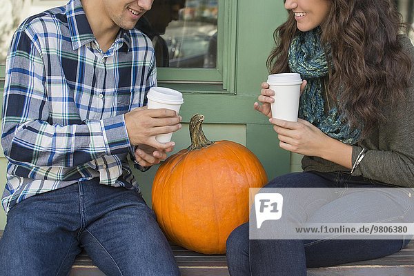 Young couple sitting on bench with coffee cups