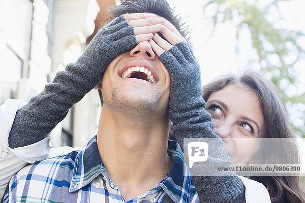 Young woman covering her boyfriend's eyes