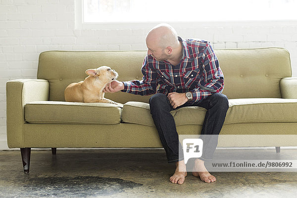 Man sitting on sofa stroking pug