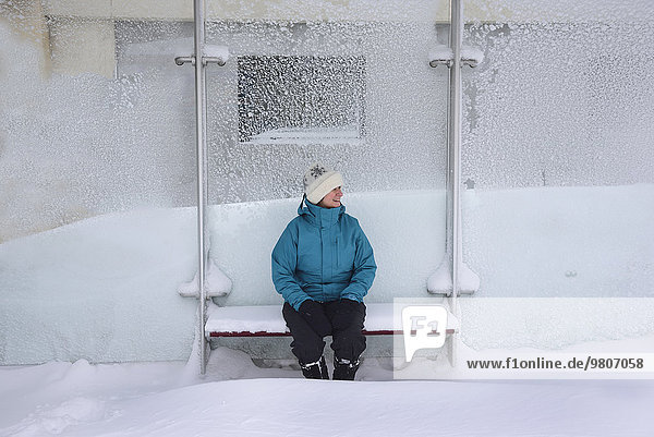 Middle aged woman sitting in bus stop  winter snow
