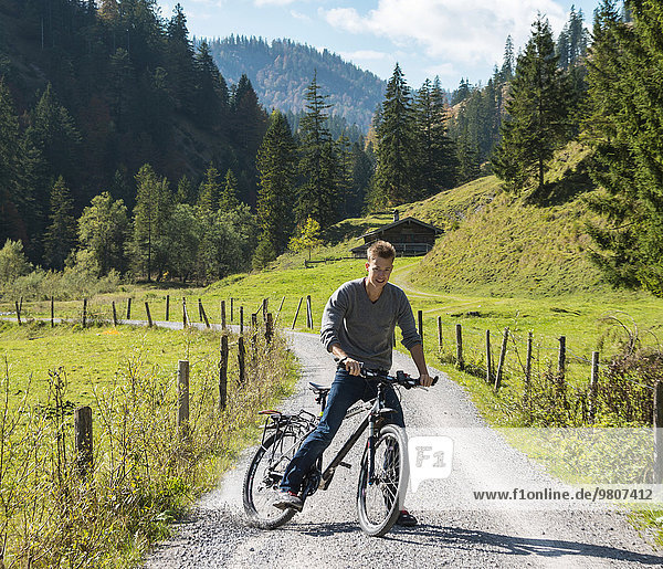 Junger Mann auf Fahrrad  Berglandschaft  Valepptal  Spitzingsee  Bayern  Deutschland  Europa