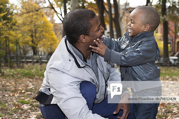 Male toddler touching fathers face in autumn park
