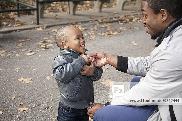 Männliche Kleinkindbefestigung Jacke Reißverschluss im Park
