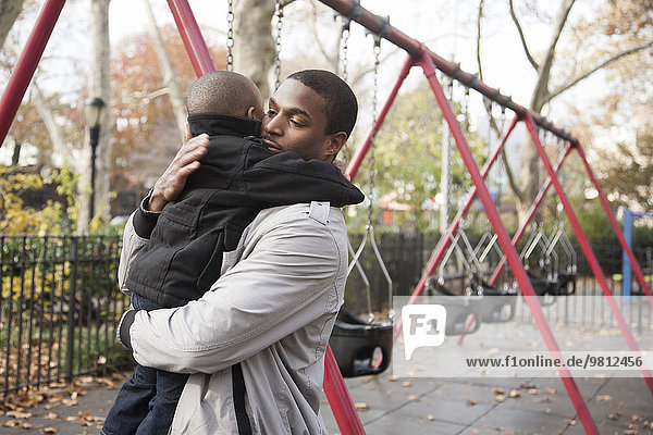Vater und Kleinkind umarmen sich im Park