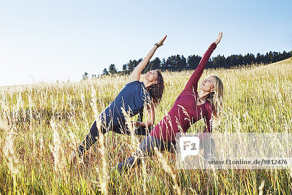 Reife Frauen  die Yoga auf dem Feld praktizieren
