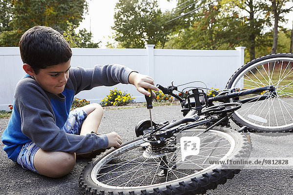 Determined boy repairing bicycle on driveway