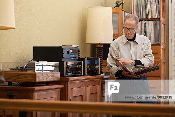 Senior man reading vinyl record cover in living room