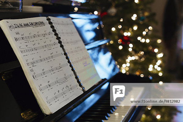 Noten auf Klavier  Weihnachtsbaum im Hintergrund