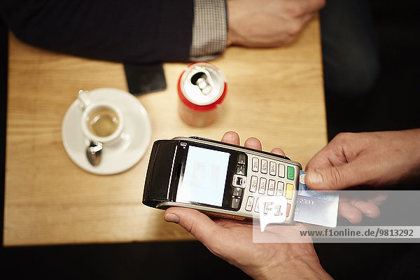 Restaurantmitarbeiter beim Einstecken der Kreditkarte des Kunden in den Kreditkartenleser