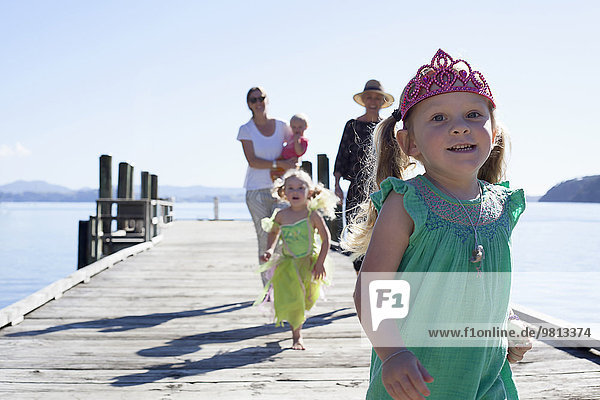 Zwei erwachsene Frauen und Töchter  die am Pier spazieren und laufen  Neuseeland