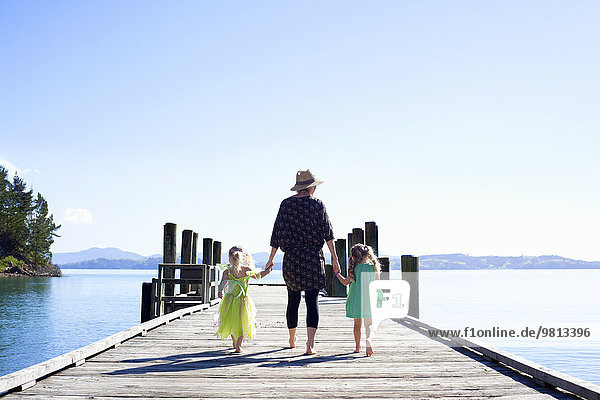 Mid adult woman and daughters strolling on pier  New Zealand