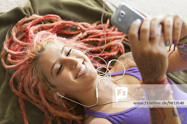 Close up of young woman with pink dreadlocks choosing music on smartphone