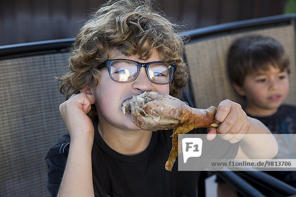 Nahaufnahme eines Jungen  der an Thanksgiving Truthahnbein isst.