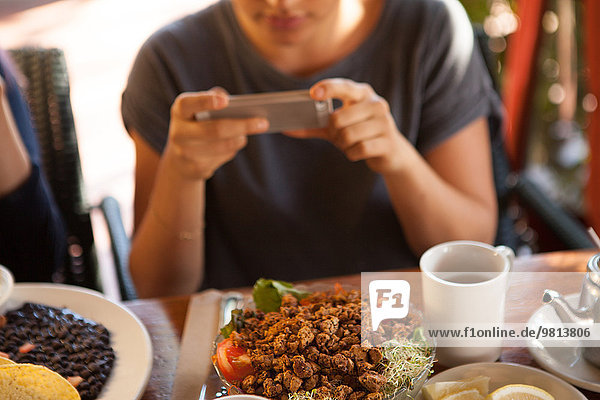 Woman taking photograph of meal in vegetarian restaurant