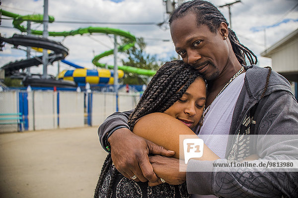 Vater umarmt Tochter im Vergnügungspark