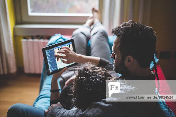 Couple lying on sofa  using digital tablet