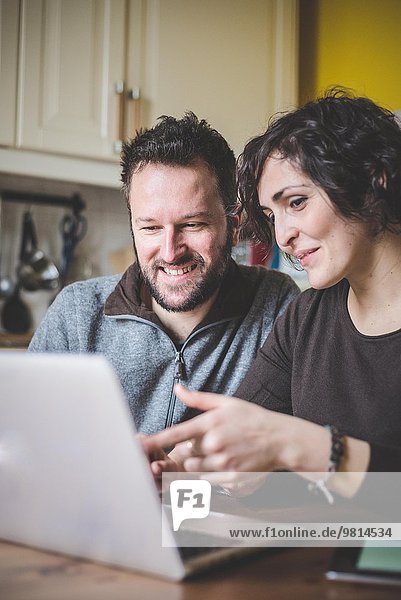 Couple sitting at table  using laptop