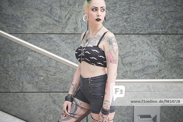 Portrait of young female tattooed punk on subway stairs