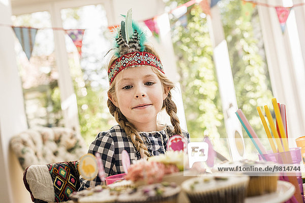Girl gazing at cupcakes at kids birthday party