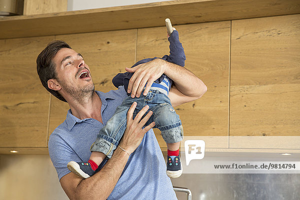 Man playing with toddler son in kitchen