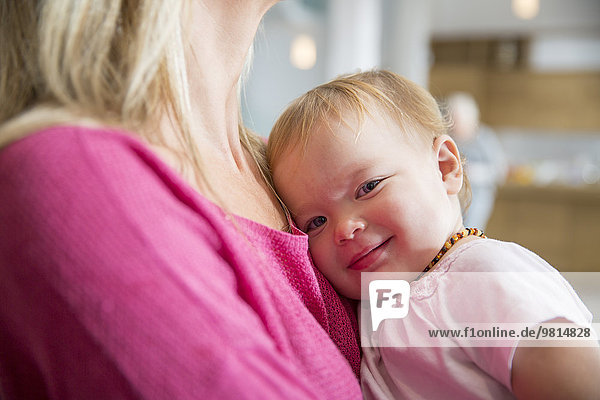 Portrait of cute female toddler in mothers arms