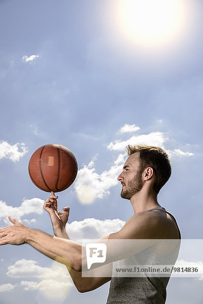 Young male basketball player spinning ball on finger