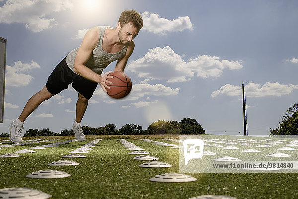 Young male basketball player doing push ups with ball on sports field