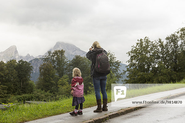 Rückansicht von Mutter und Tochter  die vom Straßenrand auf die Landschaft blicken  Berchtesgaden  Watzmann  Bayern  Deutschland